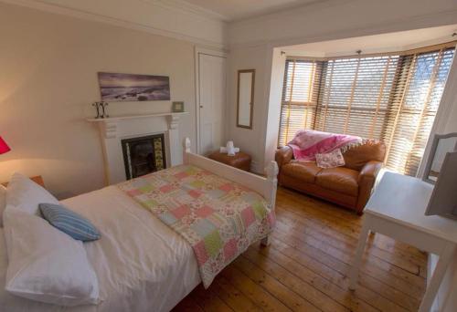 a bedroom with a bed and a couch and a fireplace at Holiday House Pembroke Dock in Pembroke Dock
