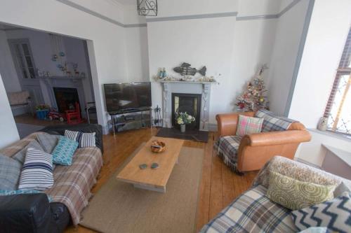 a living room with two couches and a christmas tree at Holiday House Pembroke Dock in Pembroke Dock