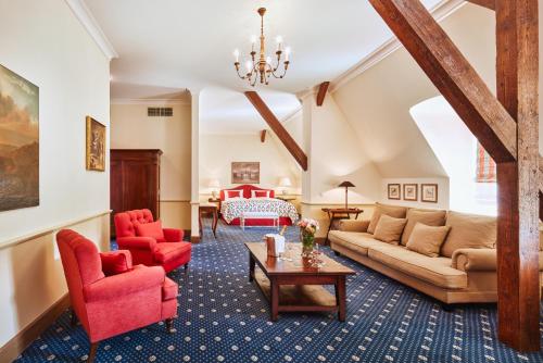 sala de estar con sillas rojas y sofá en Hotel Château Bela, en Belá