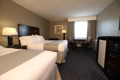 a hotel room with two beds and a desk at Clarion Pointe in Medicine Hat