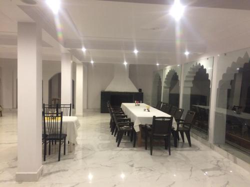 a dining room with a white table and chairs at Hotel isabel Palace in Khajurāho