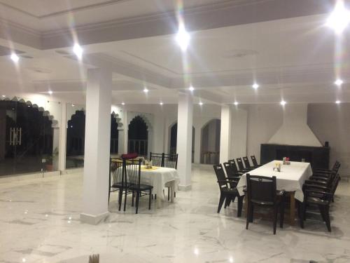 a dining room with white tables and black chairs at Hotel isabel Palace in Khajurāho