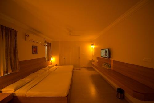 a room with three beds and a tv on the wall at Ess Pe Inn in Kāraikkudi