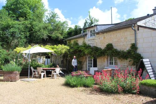 a man standing outside of a house with a table and chairs at Gite 4* L'Orée des Fleurs in Grézillé