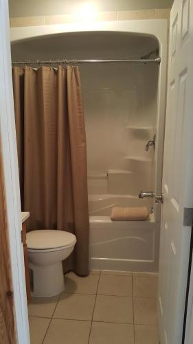 a bathroom with a tub and a toilet and a shower at Noble Motel in Norland
