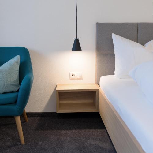 a bedroom with a bed and a chair and a lamp at Pension Löwen in Andelsbuch