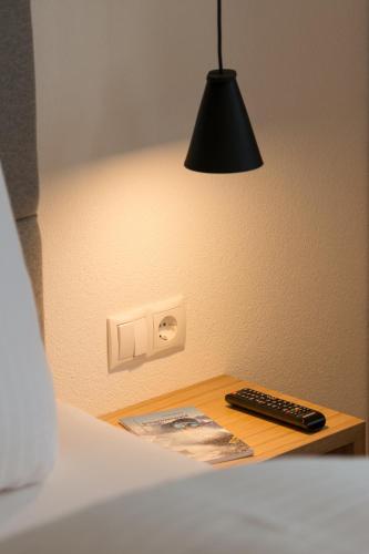 a black lamp on a table with a remote control at Pension Löwen in Andelsbuch