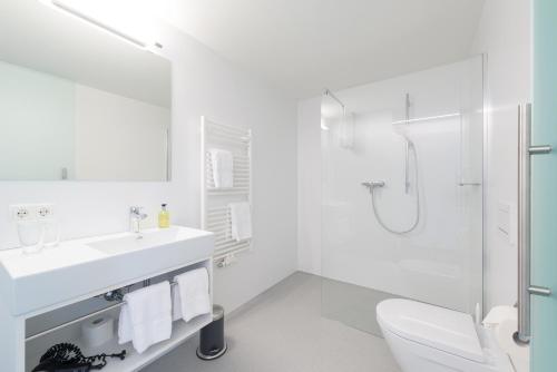 a white bathroom with a sink and a shower at Pension Löwen in Andelsbuch