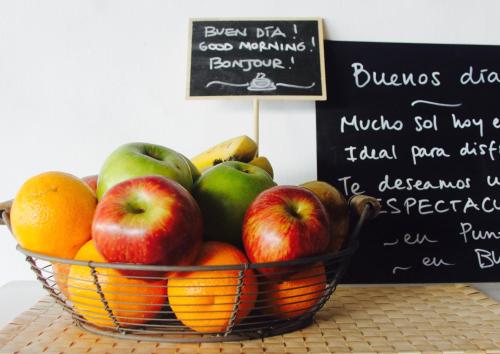 a basket of fruit on a table with a sign at Blu Inn in Punta del Este