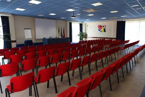 a lecture hall with red chairs and a podium at Euro Hotel in Cascina