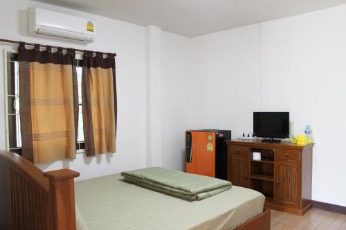 a bedroom with a bed and a desk with a television at Kaengkachan Lake Hill in Kaeng Krachan