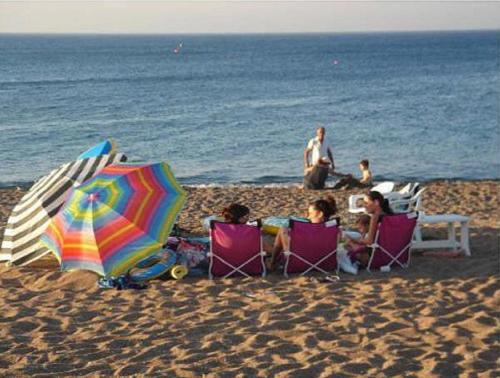 a group of people sitting in lawn chairs on the beach at The Olympians Villas in Polis Chrysochous