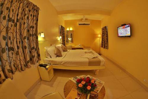 a bedroom with a bed and a table with flowers on it at Hotel Pandian in Chennai