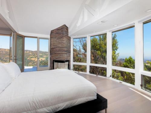 ein Schlafzimmer mit einem großen Bett und großen Fenstern in der Unterkunft Villa Woodland in Los Angeles