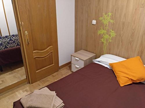um pequeno quarto com uma cama e uma porta de madeira em Madrid Rent 4 em Madri