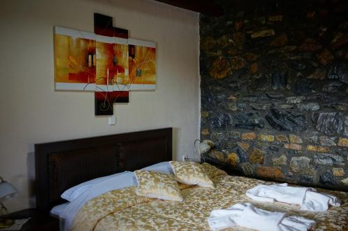 a bedroom with a bed with pillows and a stone wall at Guesthouse Sofia in Palaios Agios Athanasios