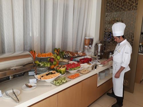 a chef standing in a kitchen preparing food at Royal Falcon Hotel in Dubai