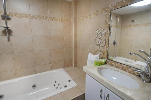 ein Badezimmer mit einer Badewanne, einem Waschbecken und einem Spiegel in der Unterkunft Family Villa in Safed