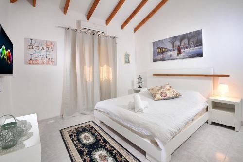 um quarto branco com uma cama e uma janela em Family Villa em Safed