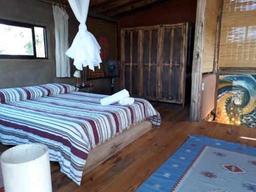 a bedroom with a bed with a striped blanket at Casa Aguai in La Paloma