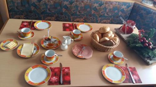 a table with plates and cups and a basket of bread at Haus Binder in Weissensee