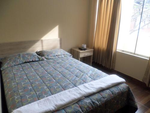 a bedroom with a bed with a blue comforter and a window at D' Barrig in Trujillo