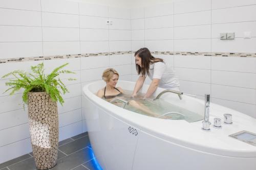 a woman in a bath tub with a girl in it at Főnix Medical Wellness Resort in Csitár