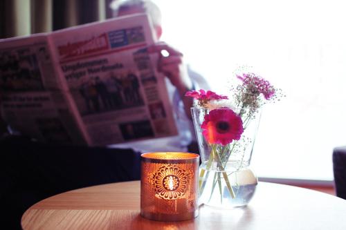 a table with two vases with flowers and a newspaper at Hotel Marena in Andenes