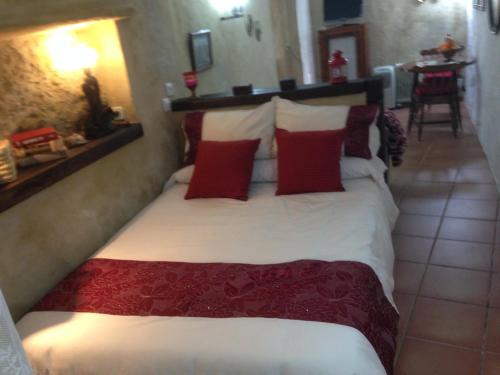1 dormitorio con 1 cama grande con almohadas rojas en Casas Andrea La Cueva, en Vejer de la Frontera