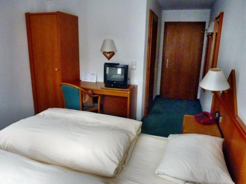 a hotel room with two beds and a desk with a television at Braunschweiger Hof in Münchberg