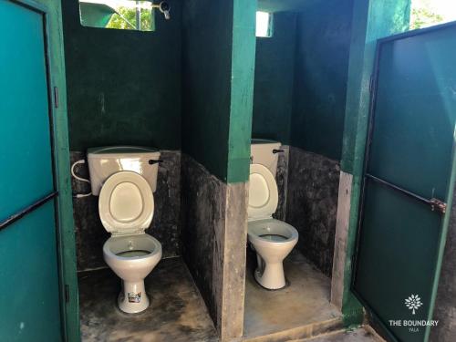 two toilets in a bathroom with green walls at The Boundary Yala in Kataragama