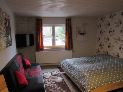 a bedroom with a bed and a chair and a window at Ferienapartments am Dorfplatz in Langscheid
