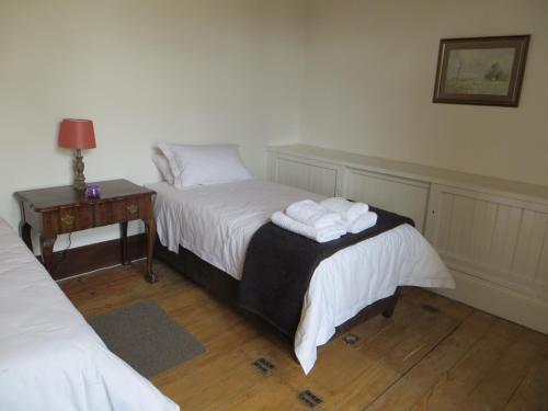 a room with two beds and a table with towels at Roode Bloem Farm House in Graaff-Reinet