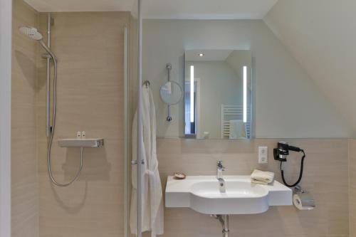 a bathroom with a sink and a shower and a mirror at Hotel am Südwäldchen in Westerland (Sylt)