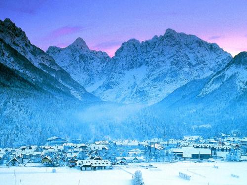a town in the snow with mountains in the background at Apartments Helena Kranjska Gora in Kranjska Gora