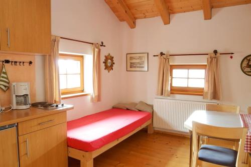 a small room with a red bed in a kitchen at Ferienwohnung Bacher in Edling