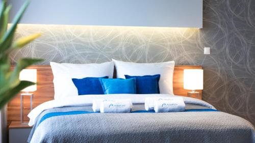 a bedroom with a bed with blue and white pillows at ActivPark Apartments in Katowice