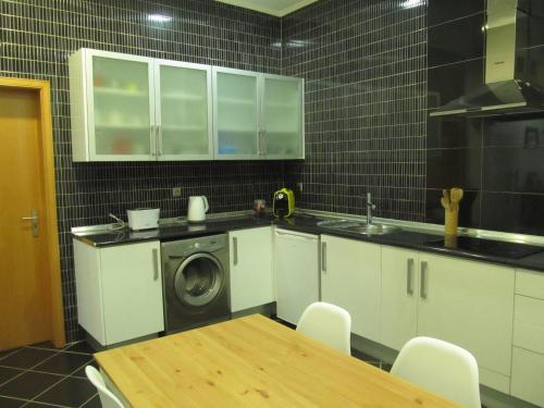 uma cozinha com uma mesa e uma máquina de lavar roupa em Casa da Ribeira em Santarém