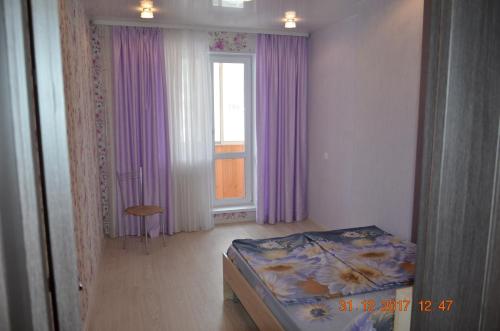 ニジニ・タギルにあるApartment on Chernoistochinskoye Shosseのベッドルーム1室(ベッド1台付)、紫色のカーテン付きの窓が備わります。