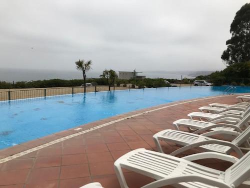a row of white chairs sitting next to a swimming pool at Vista al Mar PUCHUNCAVI in Puchuncaví