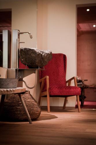 a room with a red chair and a sink at Pension Alwin in Lech am Arlberg