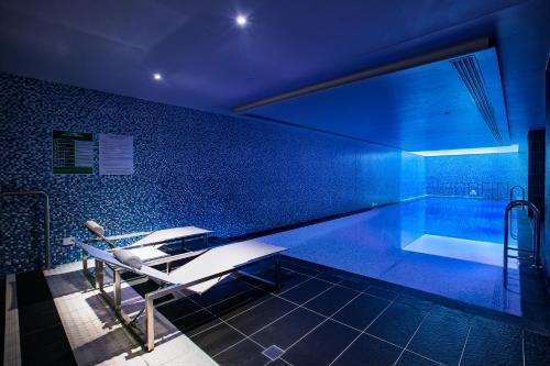 a swimming pool with a bench and a tub at Capri by Fraser Brisbane in Brisbane