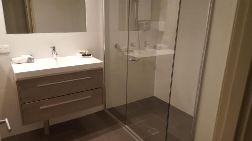 a bathroom with a sink and a glass shower at Pinnacle Apartments in Canberra