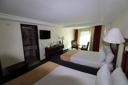a hotel room with two beds and a television at Best Western Toluca in Toluca