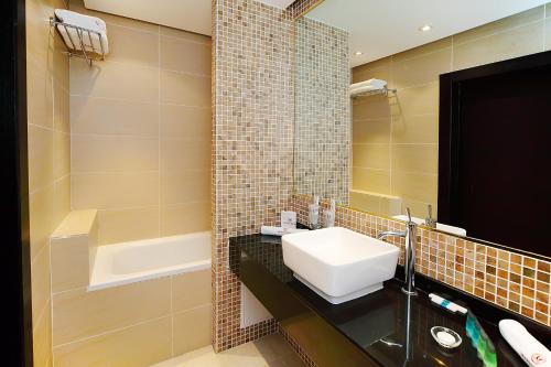 a bathroom with a sink and a bath tub at Manhattan Astana Hotel in Astana