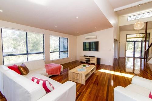a living room with a white couch and a tv at The Holiday House in K'gari Island (Fraser Island)