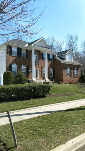 a large brick house with white columns on a street at Premier National Harbor House in Fort Washington