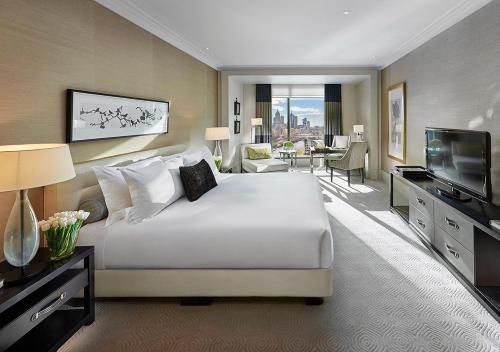 メルボルンにあるCrown Towers Melbourneのベッドとテレビが備わる広いホテルルームです。