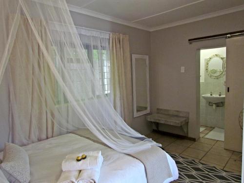 a bedroom with a bed with a mosquito net at Jasmine Cottage in George