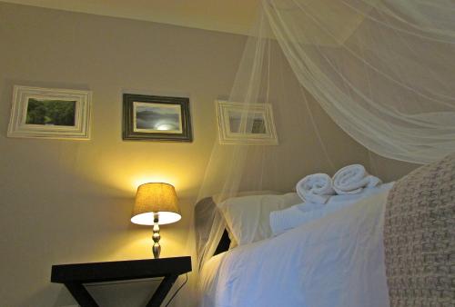 a bedroom with two beds with a lamp and a canopy at Jasmine Cottage in George